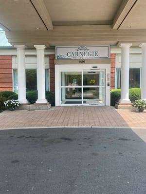 Main entrance of Carnegie Assisted Living Facility with columns and signage