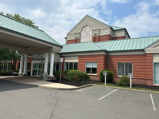 Front entrance of Carnegie Assisted Living Facility with green roofing and brick exterior.