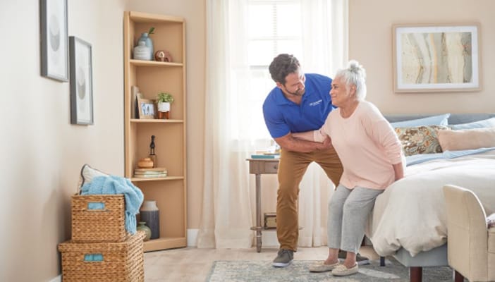 Caregiver assisting a senior woman in her bedroom