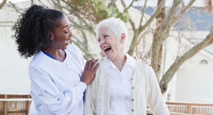 A caregiver and resident laughing outdoors