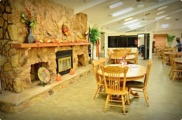 Dining area featuring wooden tables and a stone fireplace