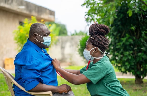 Healthcare staff assisting a resident outside in a garden