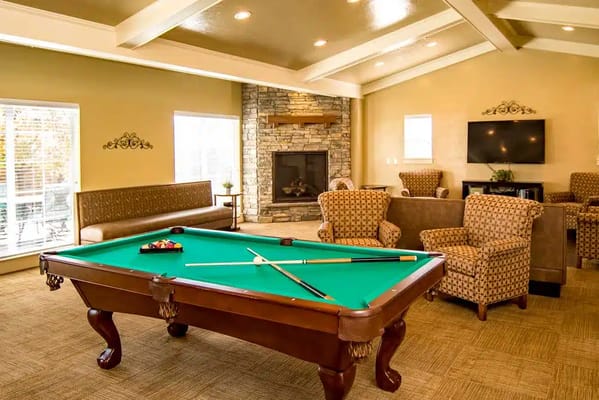 Billiards table in a cozy lounge area with seating and a fireplace