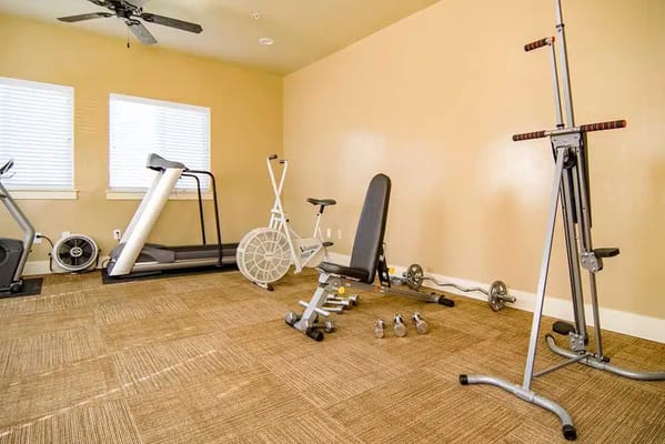 Gym with exercise equipment including treadmills, weights, and stationary bikes.