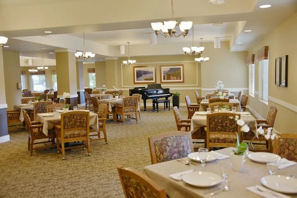 Dining area with tables set for meals and a piano in the background