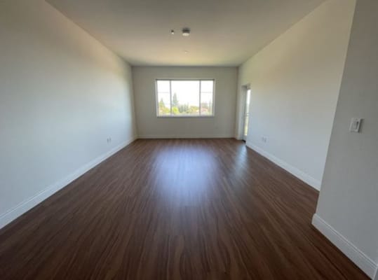 Empty room with wooden flooring and a large window