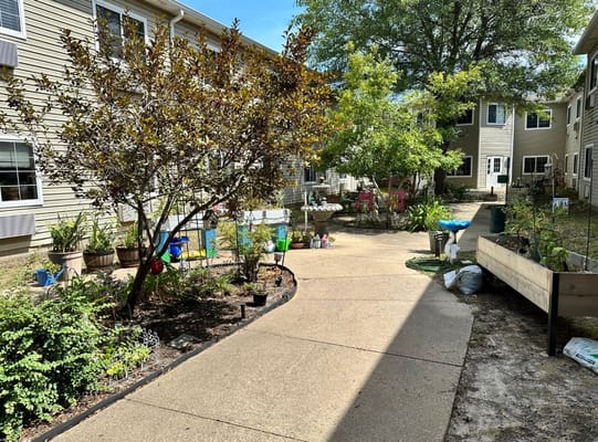 Garden path surrounded by greenery and flower pots at Garden Estates of Tyler.