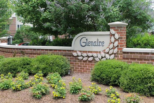The Glenaire welcome sign surrounded by greenery and flowers.