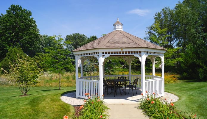 White gazebo surrounded by greenery and flowers