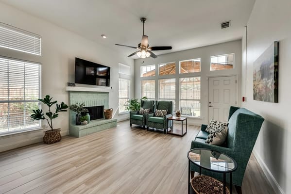Bright living room with two green chairs and a fireplace