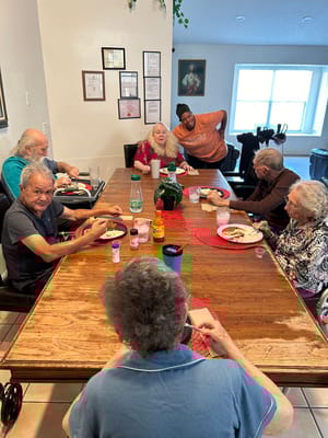 Seniors gathered around a dining table sharing a meal.
