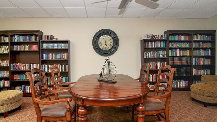 Wooden table surrounded by chairs in a library with bookshelves