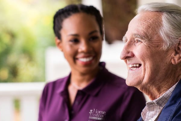 A caregiver smiling with an elderly resident outdoors