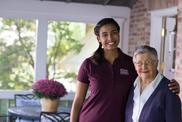 A caregiver smiling with a resident on a patio