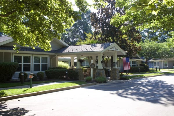 Exterior view of a senior living facility with trees and flag