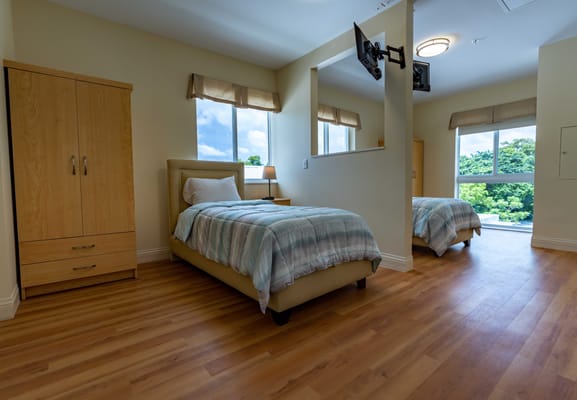Brightly lit resident room with twin beds and windows