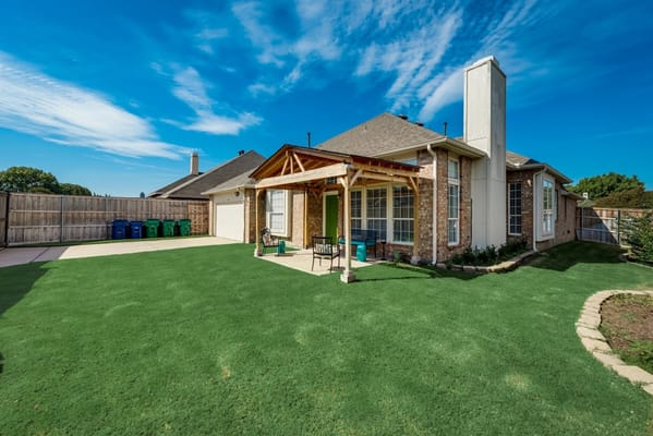 Backyard view featuring a green lawn and patio seating