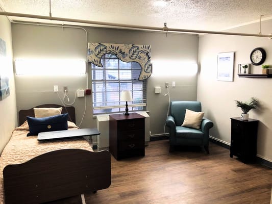 A private resident room with a bed and chair