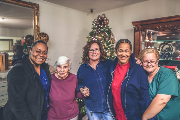 Five women posing together in front of a decorated Christmas tree