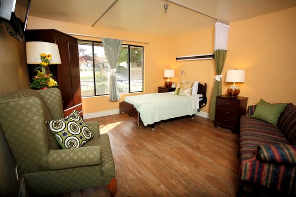 Brightly lit private resident room with furniture