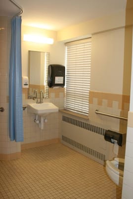 A clean, well-lit accessible bathroom with grab bars and a sink.