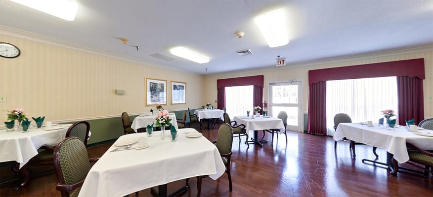 A dining area with tables set for meals, featuring flowers and green decor.