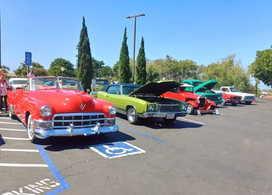 Line of classic cars including a red convertible and a green vehicle.