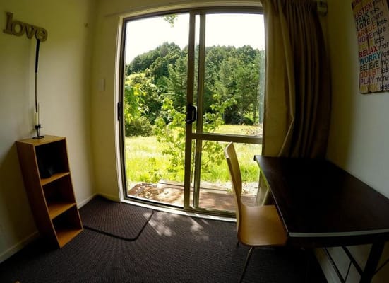 Interior view of a room with a sliding glass door opening to a natural landscape.
