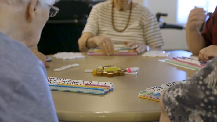 Seniors playing dominoes at a round table