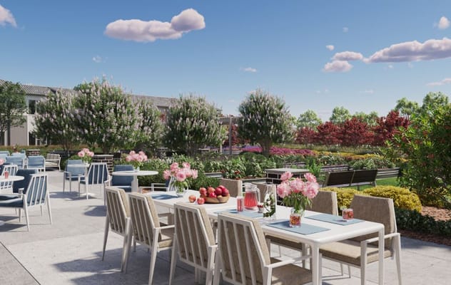 Outdoor dining area with tables, flowers, and lush greenery