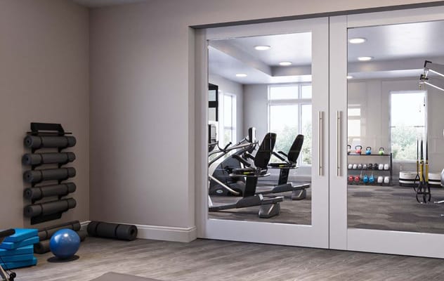 Interior view of the gym at Sonrisa Senior Living with fitness equipment and exercise mats.
