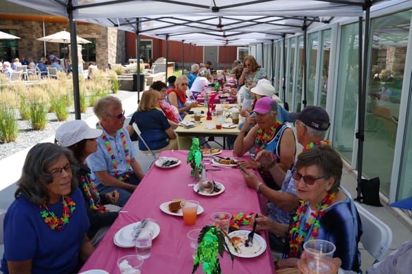 Residents enjoying a summer luncheon outdoors with colorful decorations.