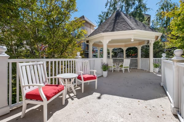 Gazebo area with white chairs and a small table in a senior living community.