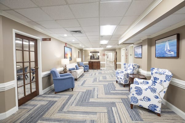 A hallway lounge with blue chairs and lamps.