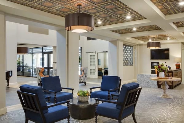 Lobby seating area with blue chairs and decorative ceiling