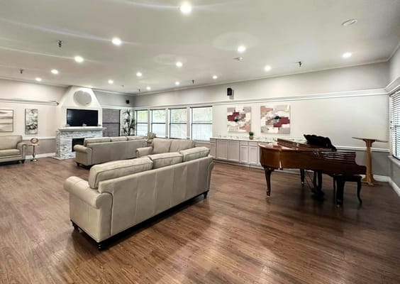 A spacious common area with seating and a piano