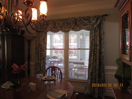 Bright dining room with a large window and floral curtains
