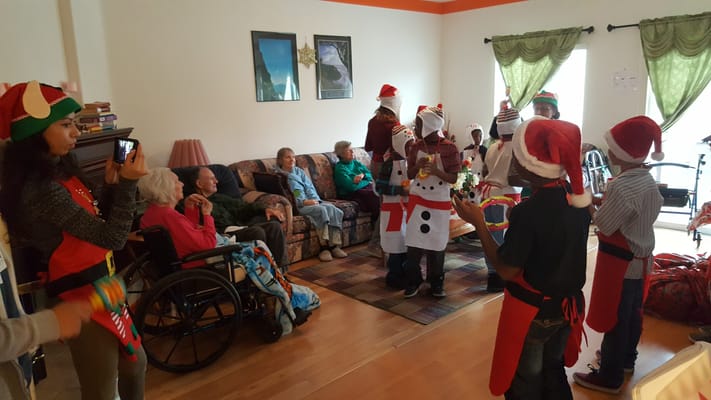 Residents enjoying a holiday performance by children in festive costumes.