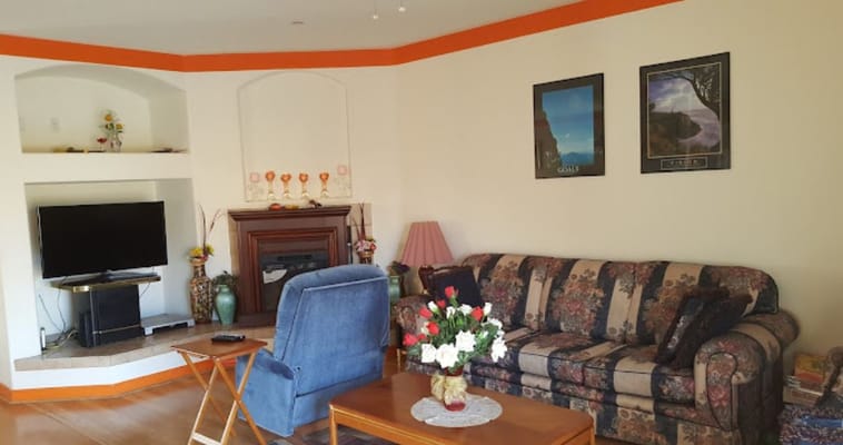 Living room with floral couch, armchair, and a TV