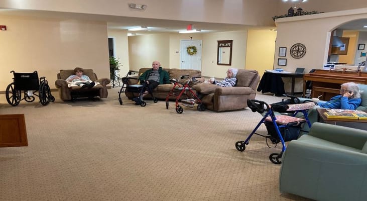 Four residents relaxing in a lounge area with mobility aids nearby.