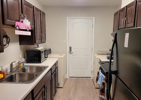 A kitchen with dark wood cabinets, stainless steel appliances, and a door leading outside.