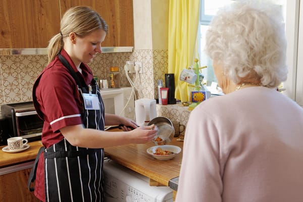 Caregiver serving food to a senior in a kitchen