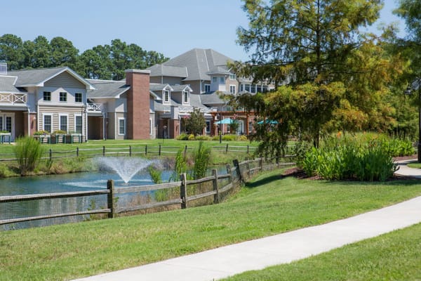 Exterior view of senior living facility with pond and landscaping