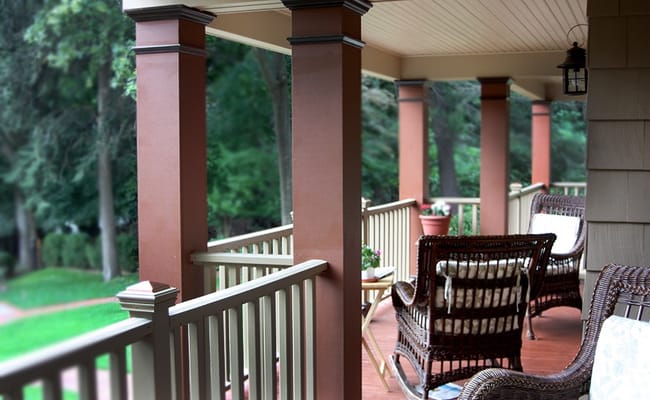 Outdoor porch area with chairs and green surroundings