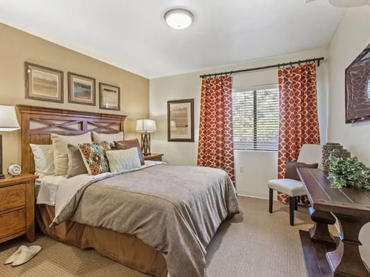 A well-decorated bedroom featuring a large bed, colorful pillows, and natural light.