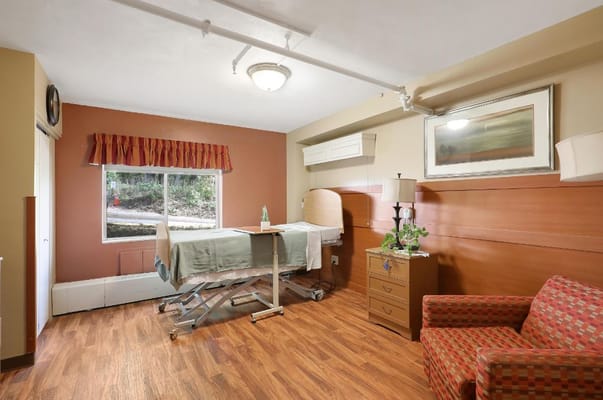 A private resident room with a bed and chair