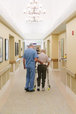 Staff assisting a resident with a walker in a hallway