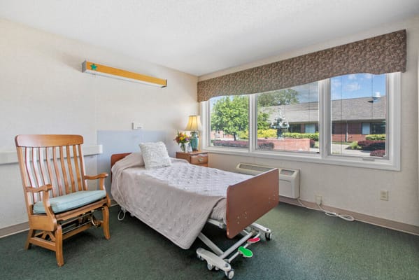 Brightly lit resident room with a bed and rocking chair