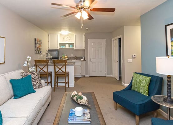 Bright living room with seating and kitchen area in The Terraces of Roseville