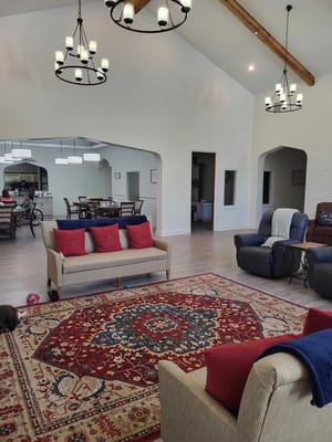 Bright and spacious common area featuring sofas, a rug, and dining tables